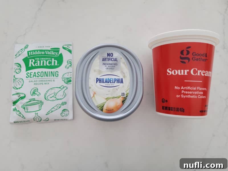 Quick 3-Ingredient Potato Chip Dip 3 Hidden Valley ranch seasoning mix, Philadelphia Cream cheese, and sour cream on a white counter.