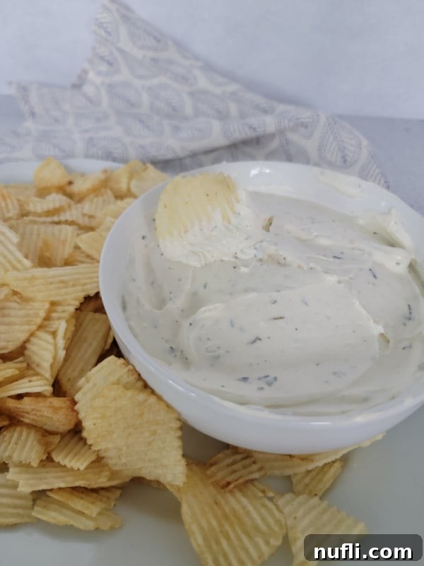Quick 3-Ingredient Potato Chip Dip 7 potato chip dipping into dip in a white bowl sitting on a white plate filled with potato chips