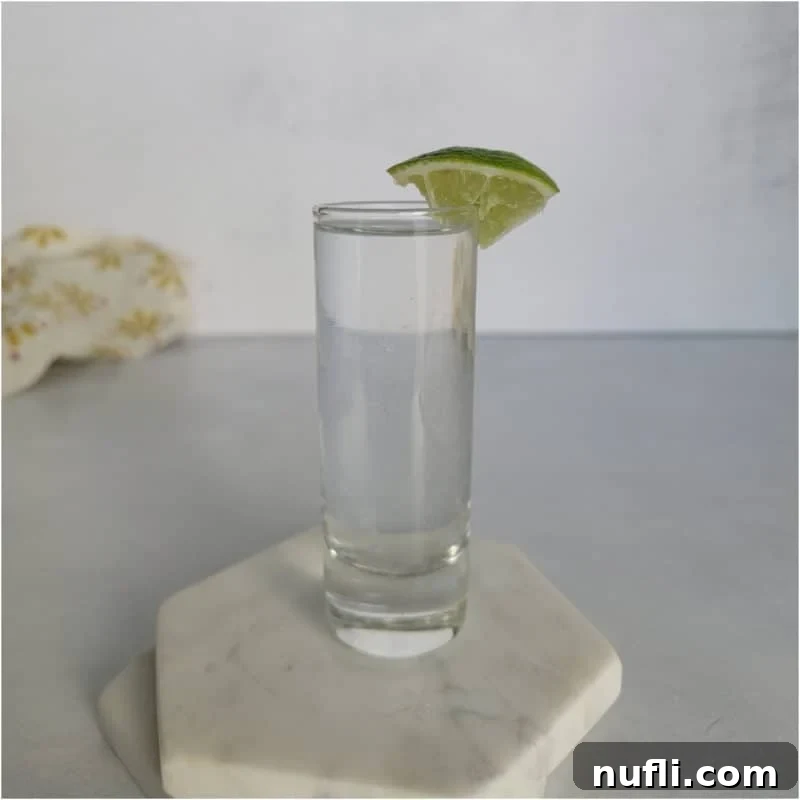 Kamikaze shot in a glass shot glass with lime wedge on white coasters