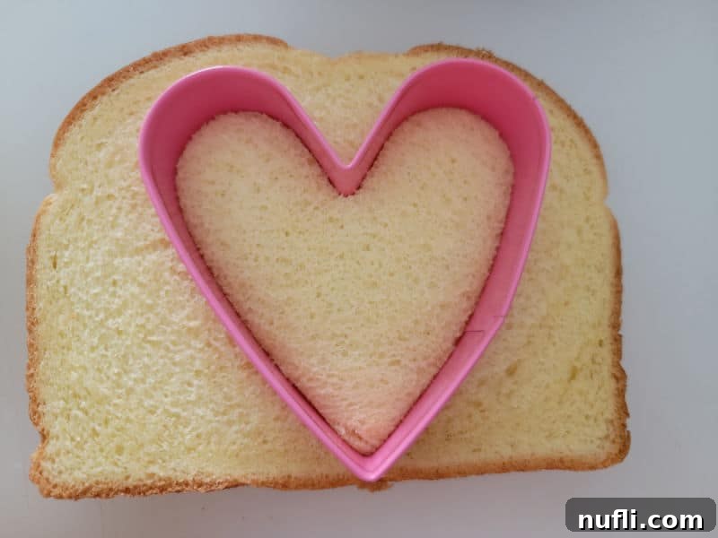 heart cookie cutter going into a slice of bread