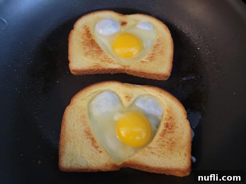 eggs in the heart cut out of two slices of bread in a skillet 