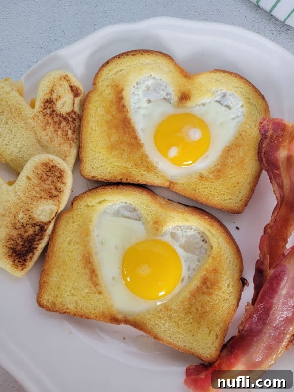 Eggs in a basket toast on a white plate next to bacon