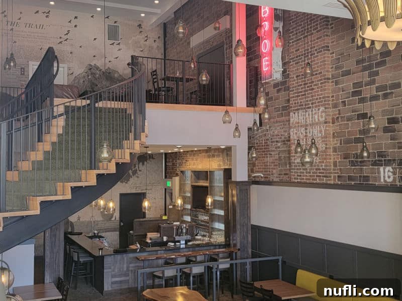 inside the hotel with a staircase leading up to seating, brick wall, bar below