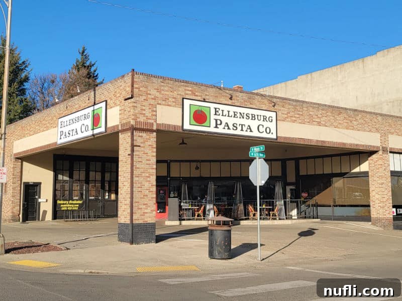 Ellensburg Pasta Co sign on a brick building with outdoor seating. 