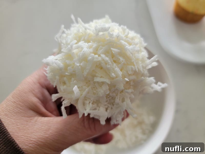 Hoppy Cupcake Delights 7 A perfectly coated cupcake, covered in shredded coconut, resembling soft white bunny fur, ready for its final decorative touches.