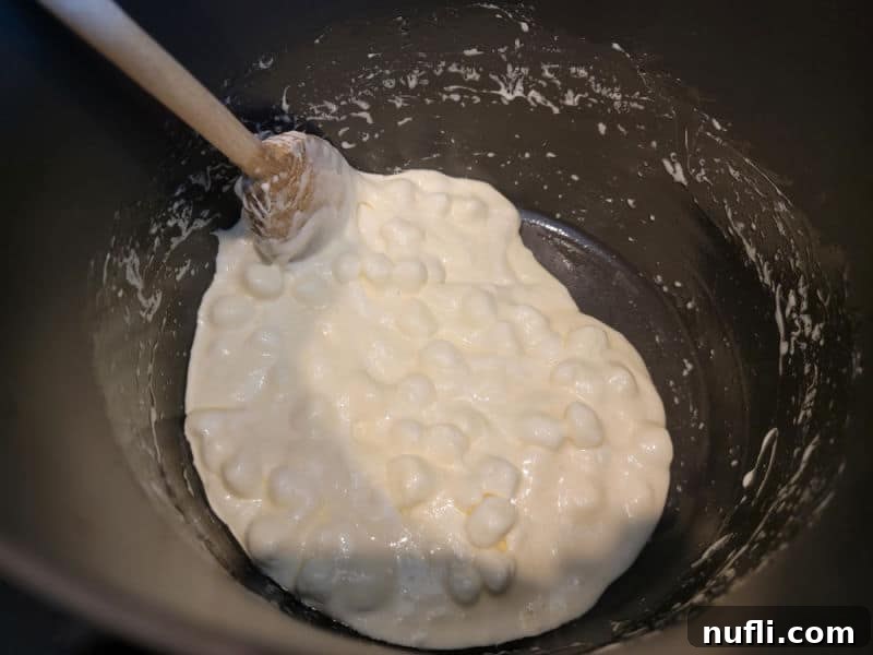 Marshmallows melting in a pot with a wooden spoon