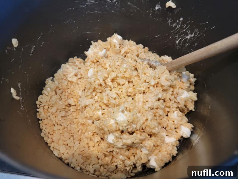 Rice Krispies in a pot with marshmallows and a wooden spoon
