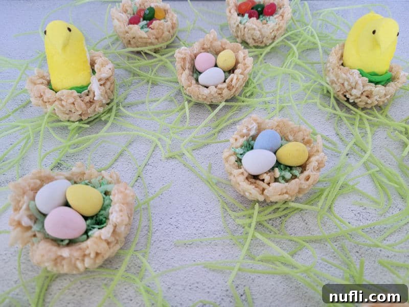 Rice Krispie nests with coconut grass, chocolate eggs, and peeps surrounded by edible grass