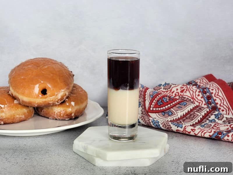 Layered shot on white coasters next to a plate of jelly donuts and a cloth napkin, ready to be served.