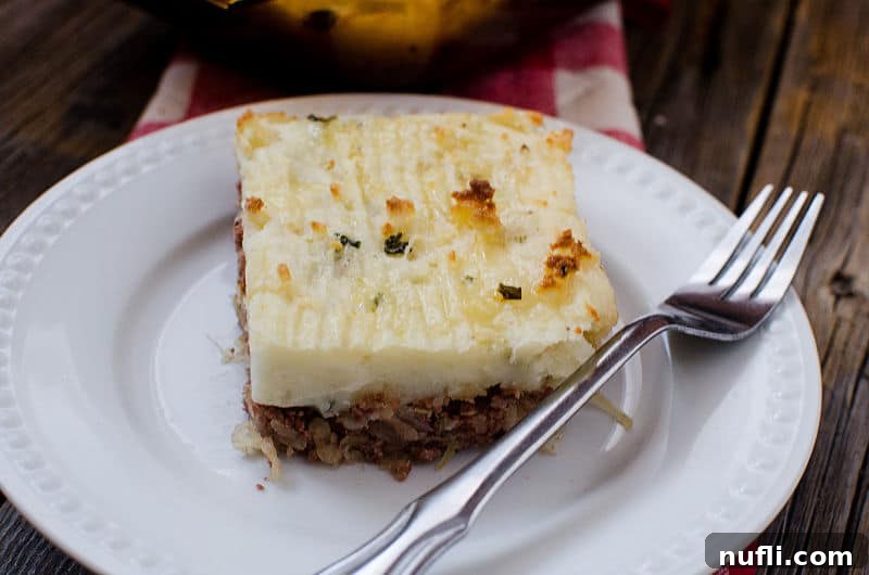 Hearty Corned Beef Shepherds Pie 8 square piece of corned beef shepherd's pie on a white plate with a fork