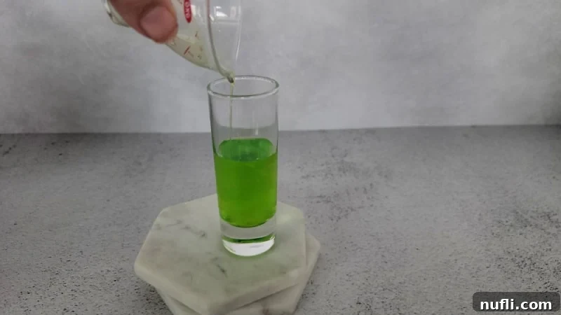 Green liquid pouring into a shot glass.