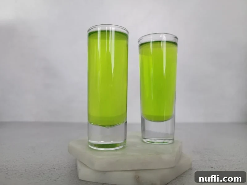 Two shot glasses filled with a green drink.