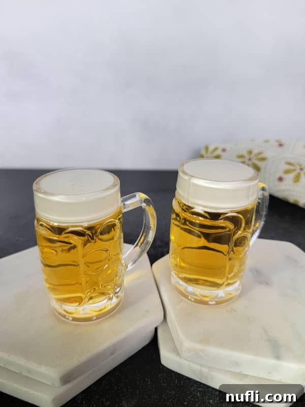 Two mini beer shots on white marble coasters. 