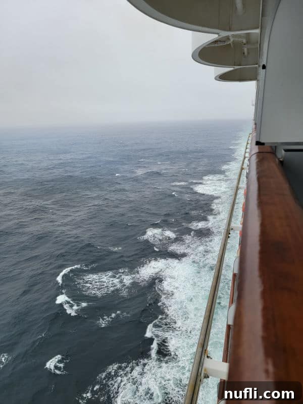 A view looking down the side of the cruise ship on a grey, slightly wavy day at sea, during the Alaska journey.