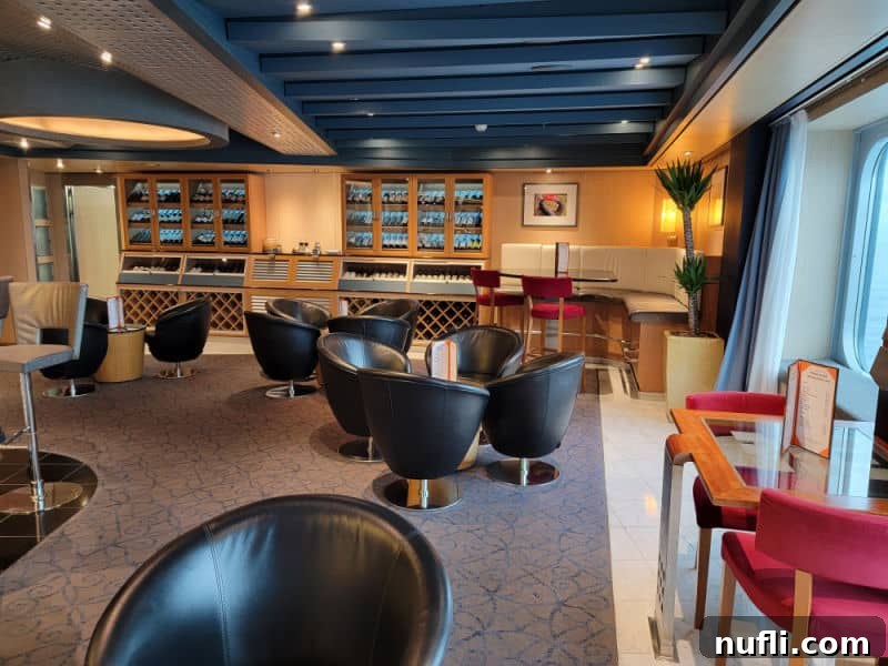 An inviting room with sleek black chairs, a display of wine bottles, and large windows offering panoramic views of the water.