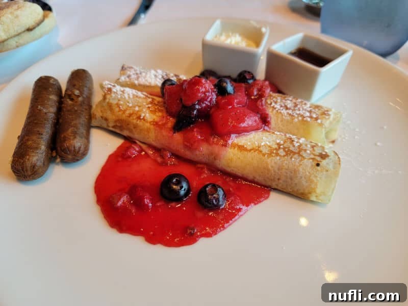 crepe with fruit, sausage, and syrup on a white plate