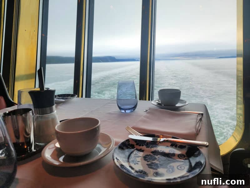 A cozy table setup looking out over the serene water from the cruise ship, perfect for enjoying the Alaskan views.