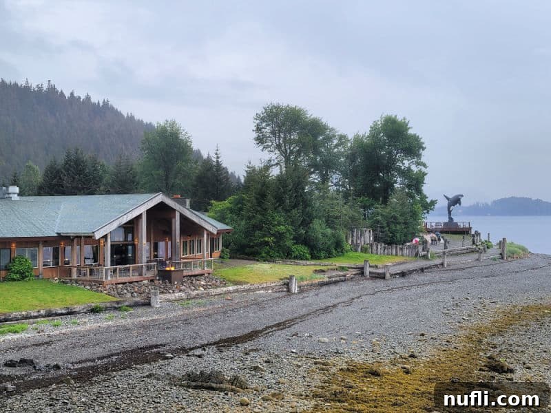 beach area with a wooden building, orca whale statue in the distance. 