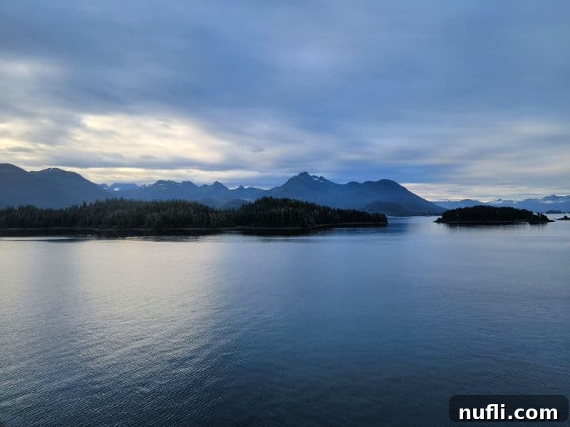 A scenic view over the water, revealing Alaskan islands and majestic mountains in the distance, a perfect backdrop for a cruise.