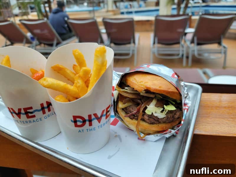 French fry containers from 'The Dive' at Terrace Grill, positioned next to a burger on a platter, showcasing a casual dining experience.