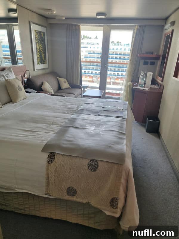 Eurodam Stateroom with bed, couch, looking out window to another cruise ship