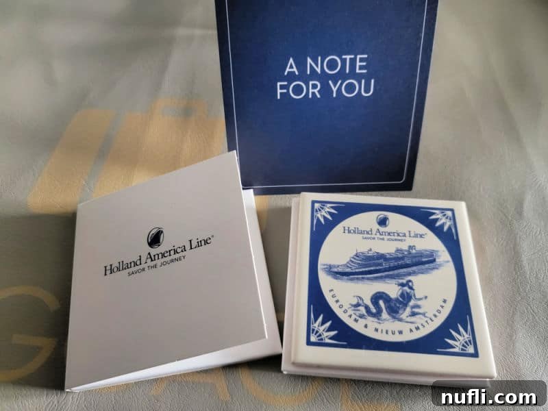Two exquisite Holland America Eurodam and Nieuw Amsterdam Delft ceramic coasters, presented alongside a welcome card, symbolizing a memorable first cruise.