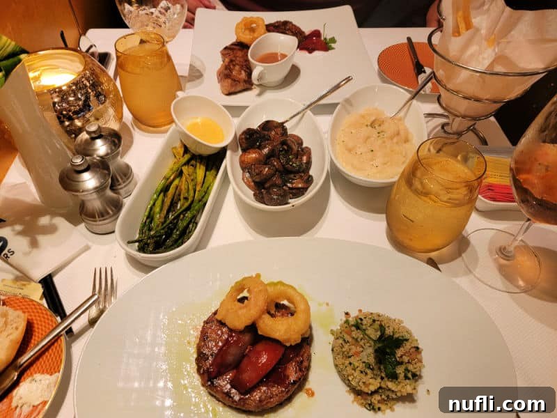 A beautifully set table laden with various plates including steak, fresh asparagus, sautéed mushrooms, drinks, and more, promising a delightful dining experience.