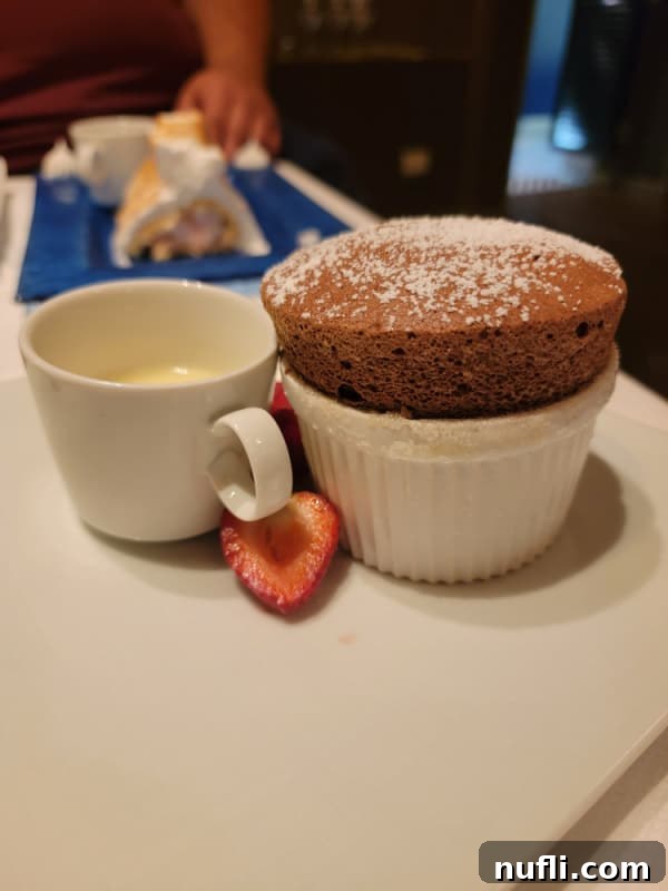 Chocolate Souffle in a white bowl next to a cup of cream and strawberrr