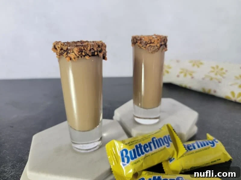 Butterfinger Bliss Shot 7 Two Butterfinger Shots on white coasters next to mini Butterfinger Chocolate bars
