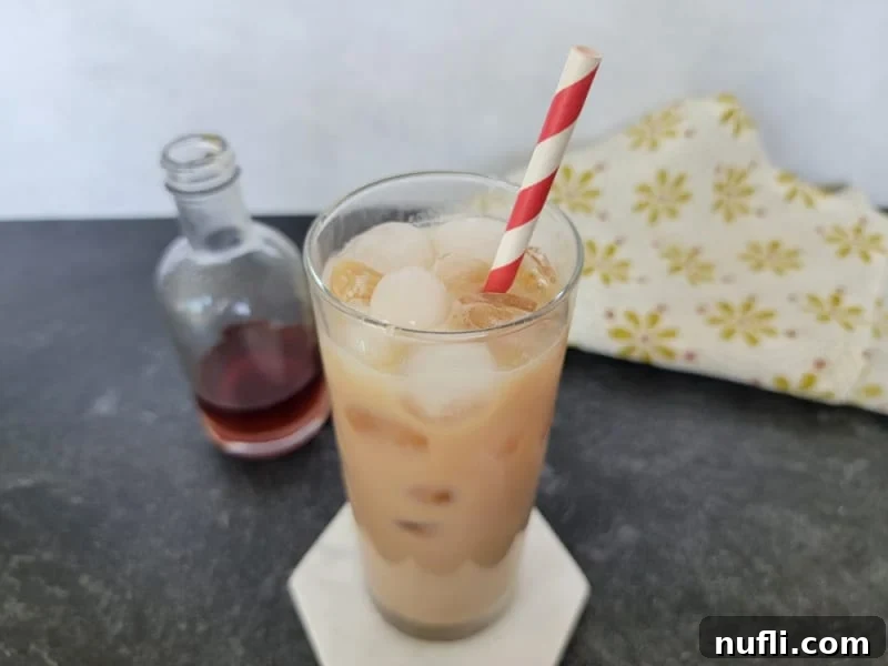 Iced chai in a tall glass with a striped straw