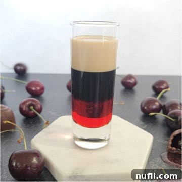 Layered red, brown, and cream shot surrounded by chocolate covered cherries