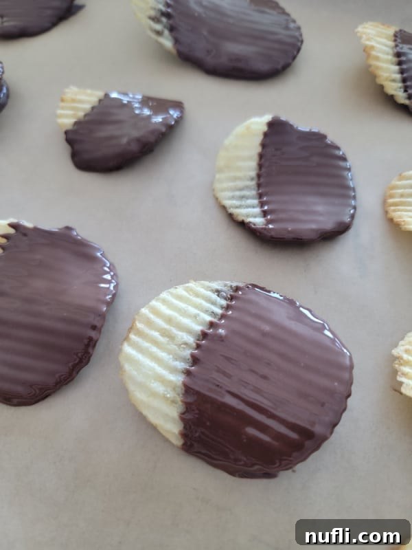 Close-up of Ruffles potato chips being carefully dipped into a bowl of melted chocolate, ready to be placed on parchment paper.