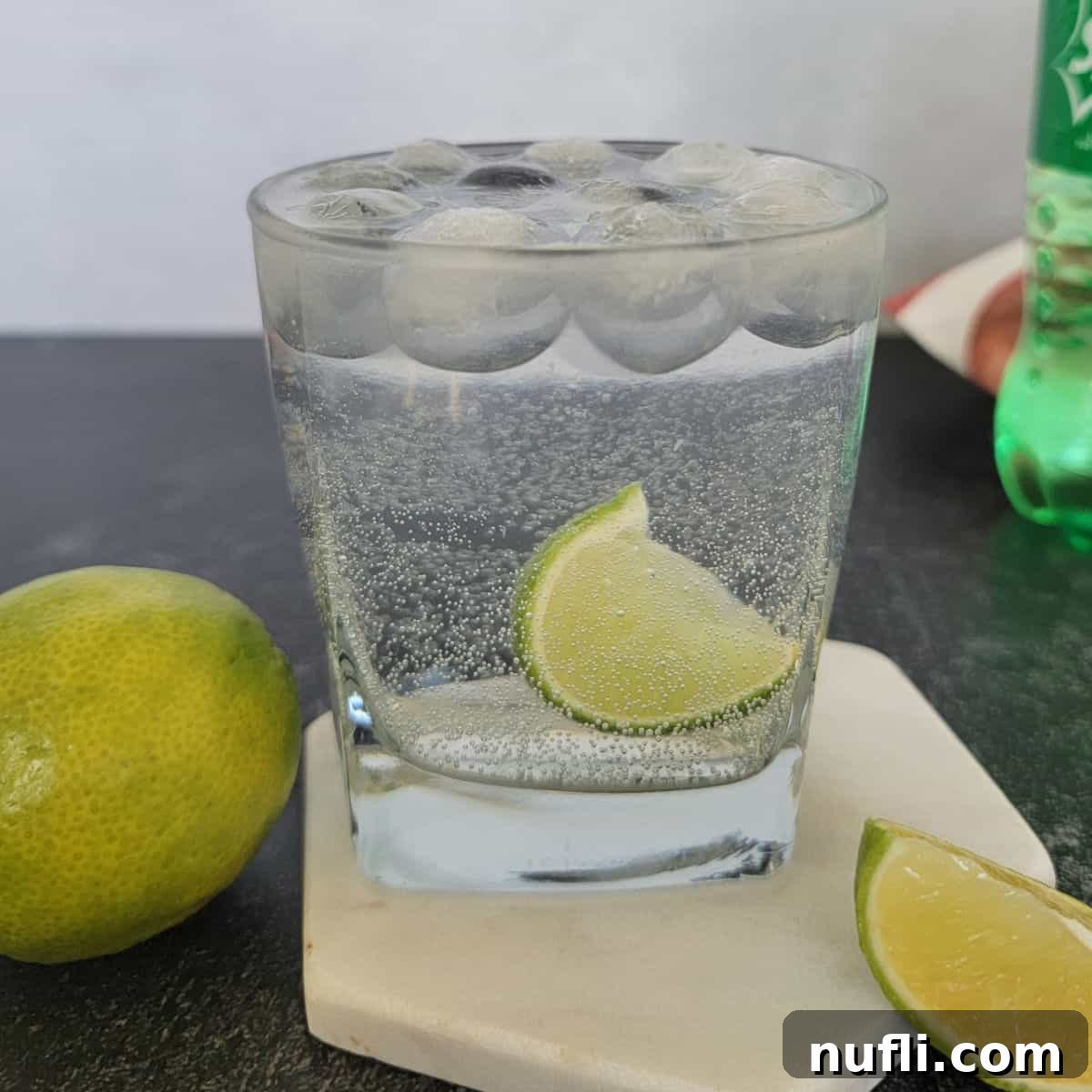 Sparkling Vodka Refresher 9 Vodka and Sprite Cocktail with a lime wedge on a coaster next to a lime