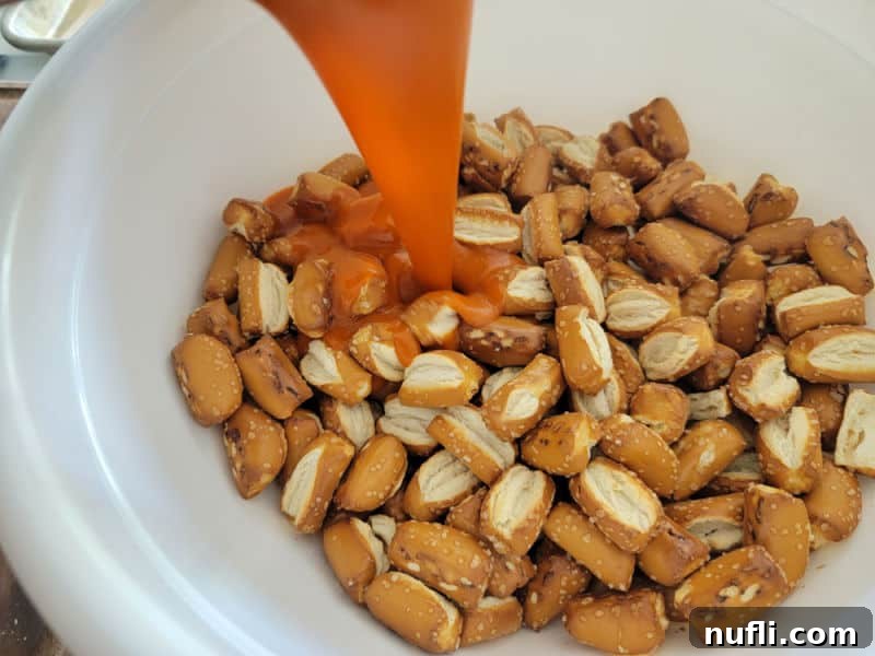 hot sauce pouring over pretzel nuggets in a white bowl
