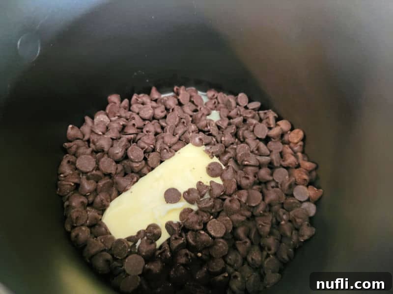 Chocolate chips and butter melting in a dark pan for no bake church window cookies