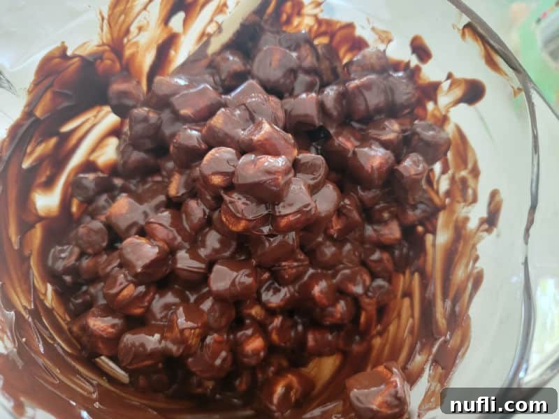 Marshmallows coated in milk chocolate in a glass batter bowl for no bake church window cookies