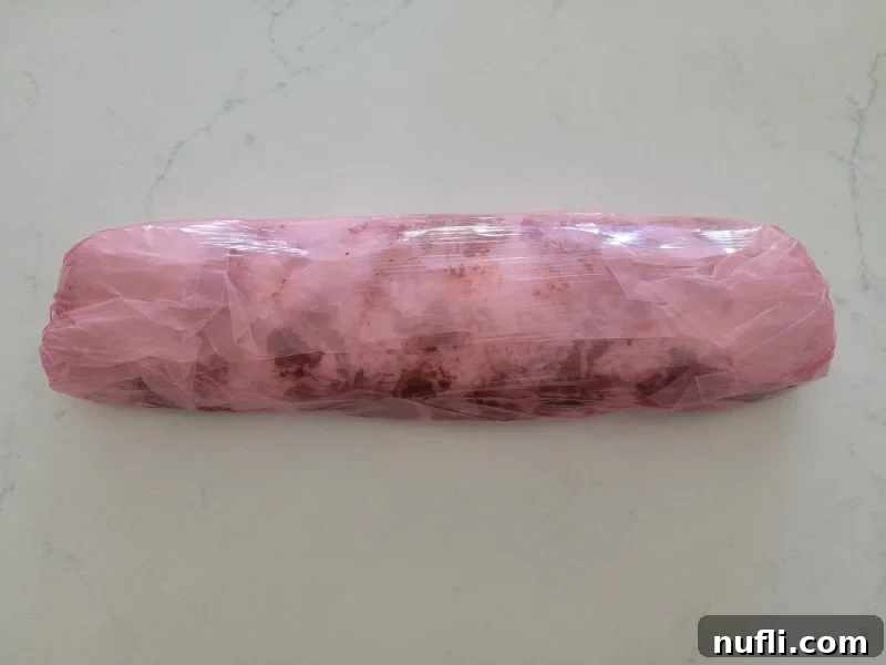 Red saran wrap plastic coating wrapped around a log of no bake church window cookies