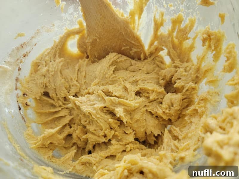 pumpkin snickerdoodle cookie dough in a glass bowl with a wooden spoon