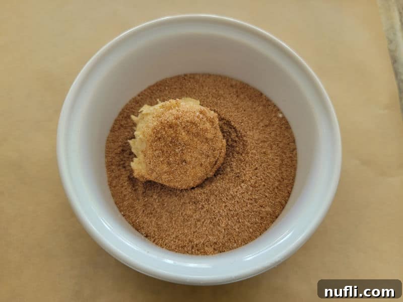 pumpkin snickerdoodle cookie dough ball in pumpkin pie spice in a white bowl