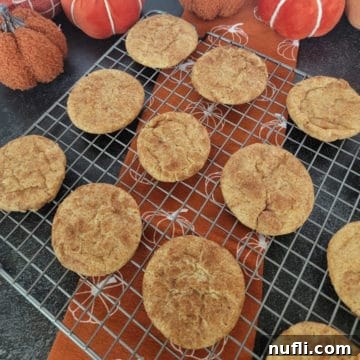 Pumpkin Snickerdoodles on a wire rack over a pumpkin napkin with cloth napkins in the background