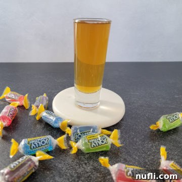 Jolly Ranch Shot on a white coaster surrounded by Jolly Rancher Candy