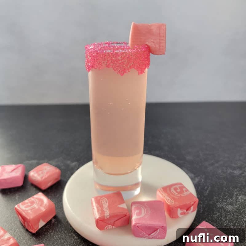 Pink Starburst Shots and Cocktails 2 Pink Starburst Shot on a white coaster surrounded by Starburst candies