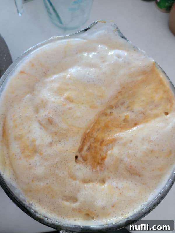 A light and airy angel food cake batter in a clear glass mixing bowl, showing its readiness for the next steps in creating a delicious dessert.