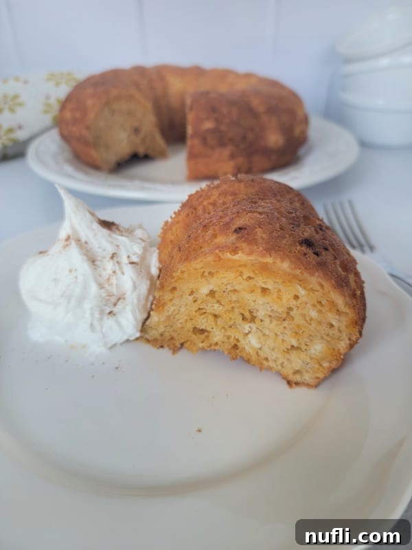 A delightful slice of pumpkin angel food cake elegantly presented on a white plate, topped with a generous swirl of whipped cream, inviting indulgence.