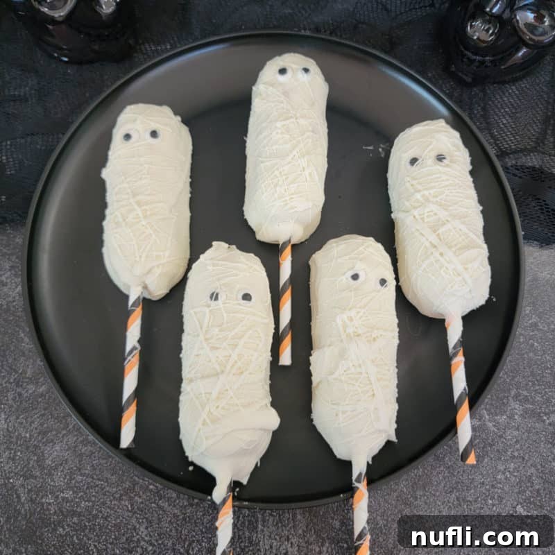 Twinkie Mummies on a black circle plate, a perfect Halloween dessert