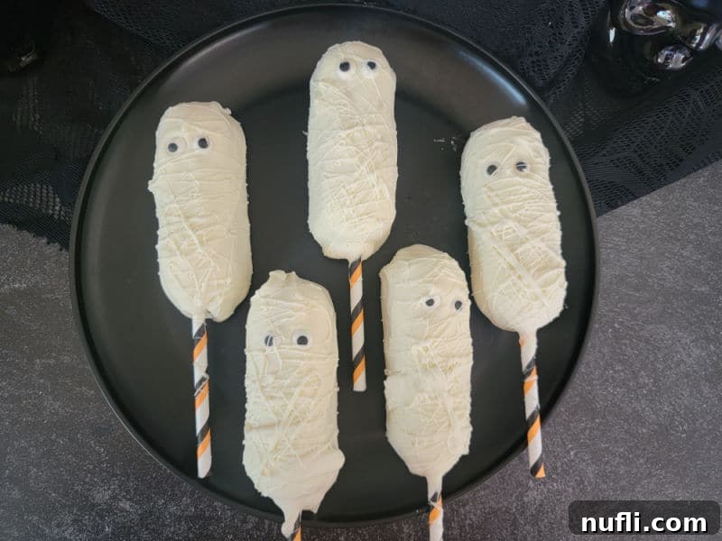 Mummy Twinkies on a black circle plate, ready to be served at a Halloween party