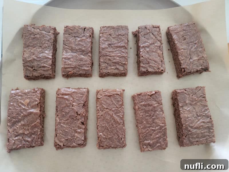 Brownie rectangles neatly arranged on parchment paper, ready for decorating