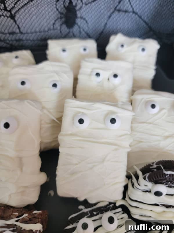Monster Mummy Krispie Treats 7 Mummy Rice Krispie treats stacked next to Mummy Oreos on a platter, offering more Halloween treat ideas.
