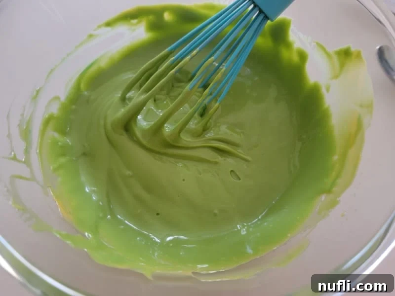 Green cheese sauce with a blue whisk in a glass bowl