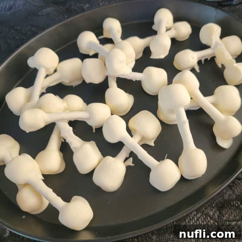 Halloween Pretzel Bones covered in white chocolate on a black platter, a perfect spooky dessert